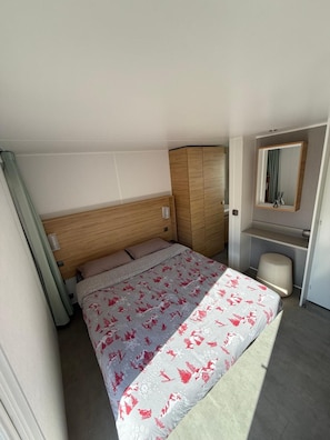 A bedroom with a bed, a wooden wardrobe, a mirror, and a small seating area. - 5-Star Camping Domaine de la Yole, 500m from the Beach in Valras-Plage (Vendres)