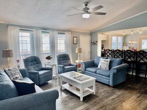 A living room with two sofas, a coffee table, and a ceiling fan. - 3bd/2bth home in Keys @ OceansideVillage-3 min walk to the beach! Golfcart avail (Surfside Beach)