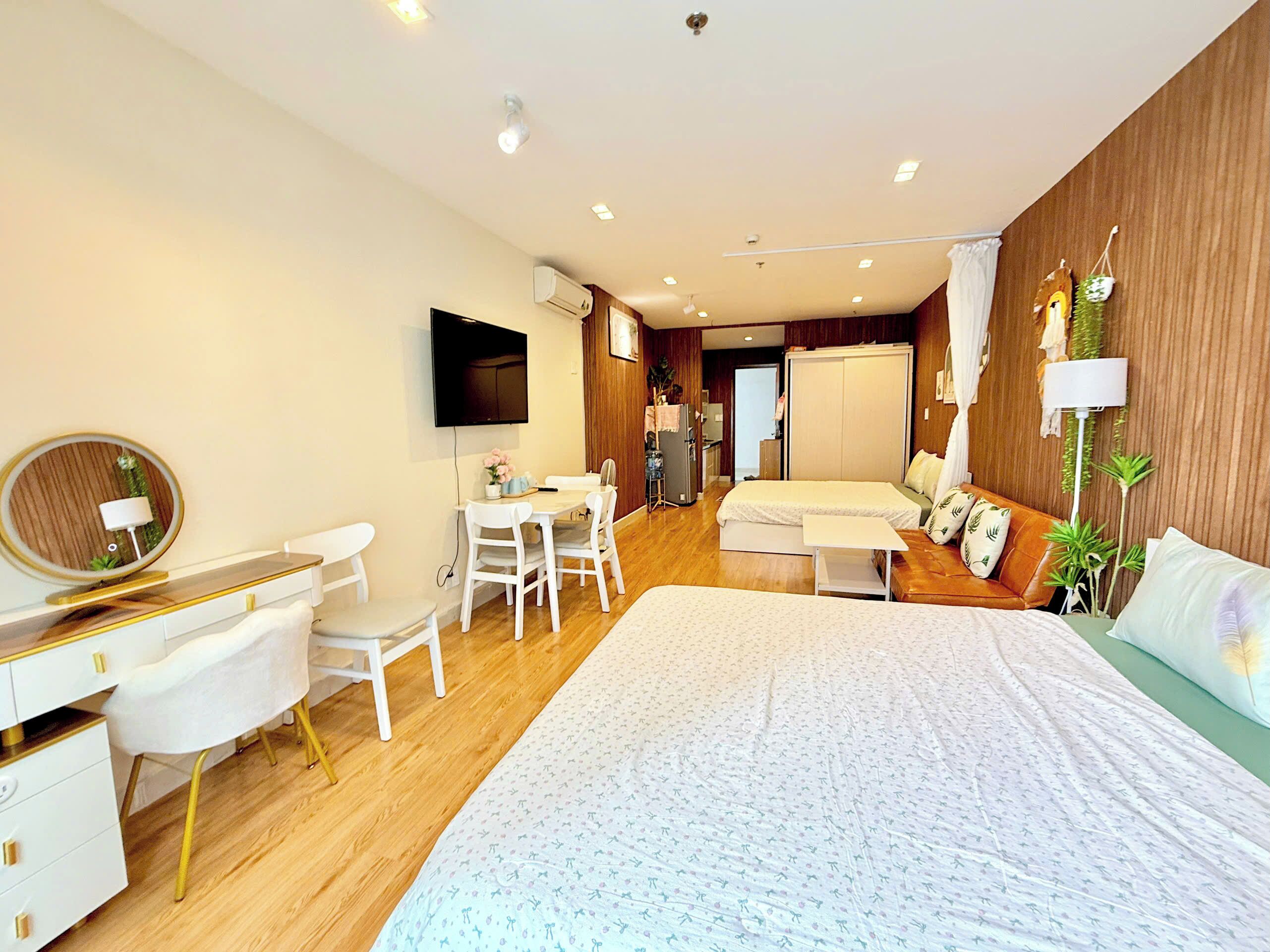 A modern bedroom with a bed, desk, chairs, and a television.