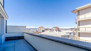 Une terrasse sur le toit offrant une vue sur le paysage urbain et les montagnes au loin.