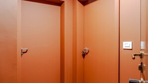 Une pièce avec deux portes fermées, un interrupteur visible et une poignée métallique sur la porte de droite.