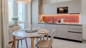 Une cuisine moderne avec un coin repas, dotée d’une grande fenêtre, d’un luminaire suspendu et d’un four à micro-ondes.