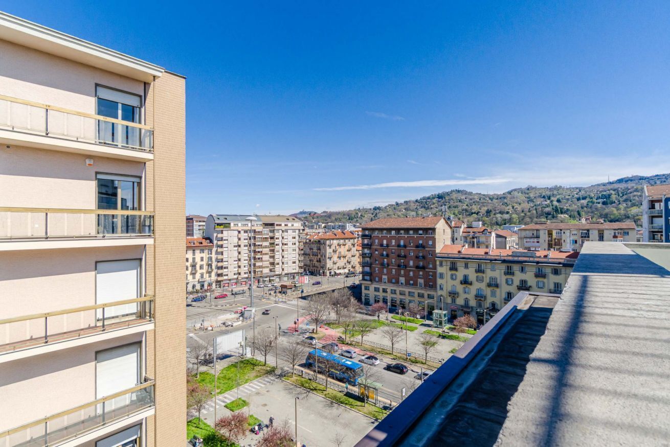 Ein mehrstöckiges Gebäude mit Balkonen, einem Parkplatz und Blick auf eine hügelige Landschaft.