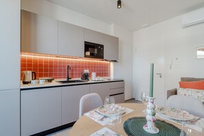 A modern kitchen with a microwave, a coffee maker, and a sink. There is a dining table with a vase and a candle. - A welcoming and functional studio, conveniently located in a area with excellent metro access, perfect for reaching the city center in just a few minutes and easily traveling to San Salvario. The location is also ideal for those needing to reach the Po R (Turin)