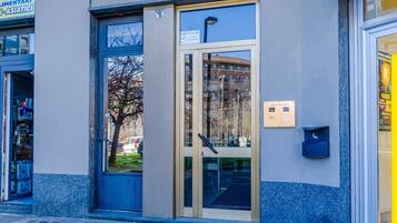 A building entrance with a glass door, a mailbox, and a sign indicating the entrance.