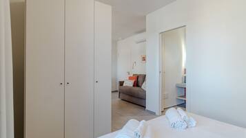 A hotel room with a bed, a wardrobe, a sofa, and a bathroom.