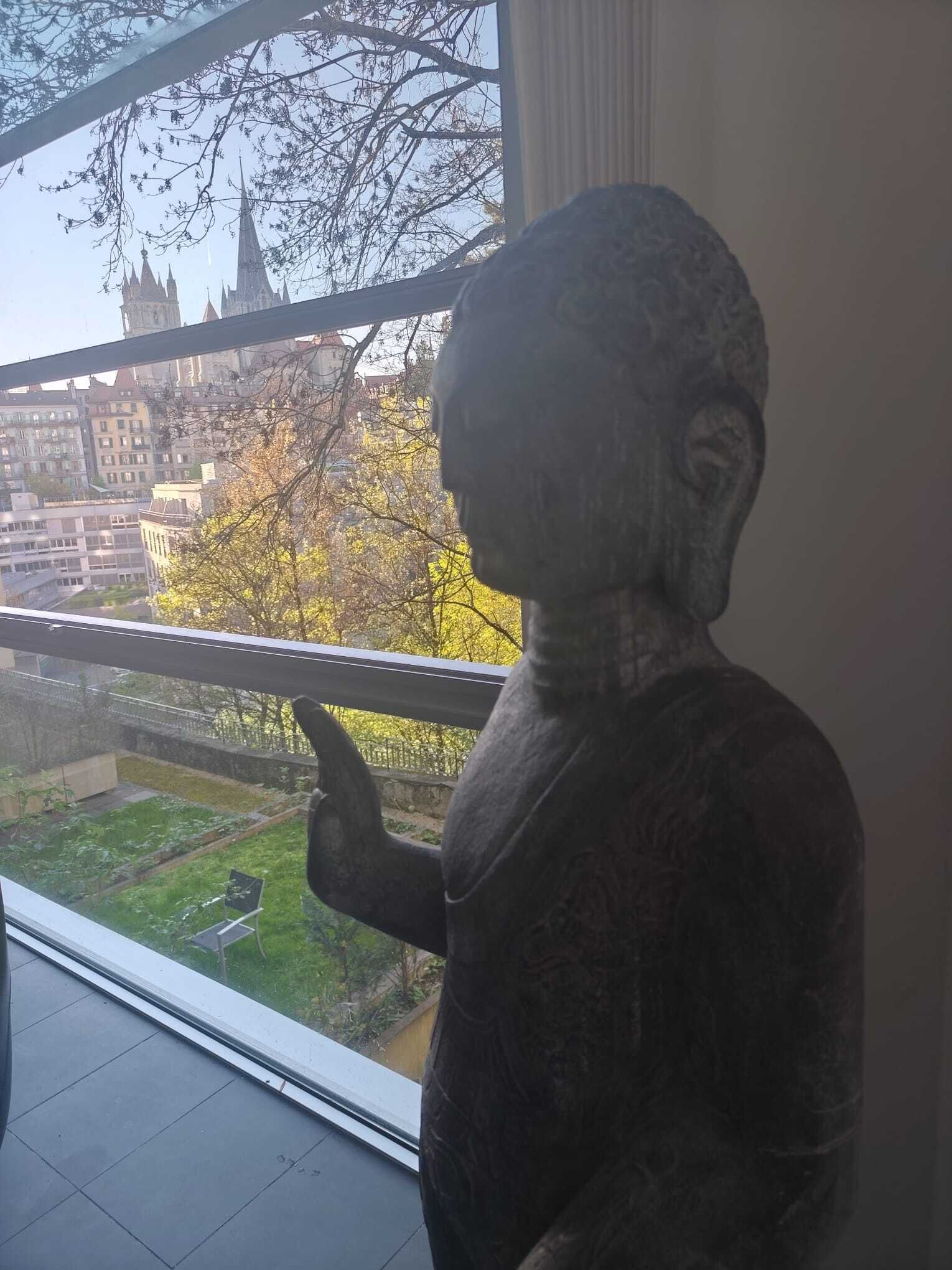 A statue in a room with a large window overlooking a cityscape.