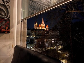 A view of a historic building with multiple spires, seen through a window with a leather couch in the foreground. - Luxury Duplex with Rooftop & Cathedral View – Central Lausanne (Lausanne)