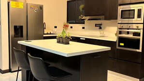 A modern kitchen with a central island, black chairs, a refrigerator, an oven, and a microwave. - House Airy Luxury+WiFi+Amazing View At Alajuela CR (Provincia de Alajuela)