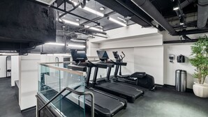 Et moderne fitnessrum med løbebånd, en motionscykel og gelænder i glas.