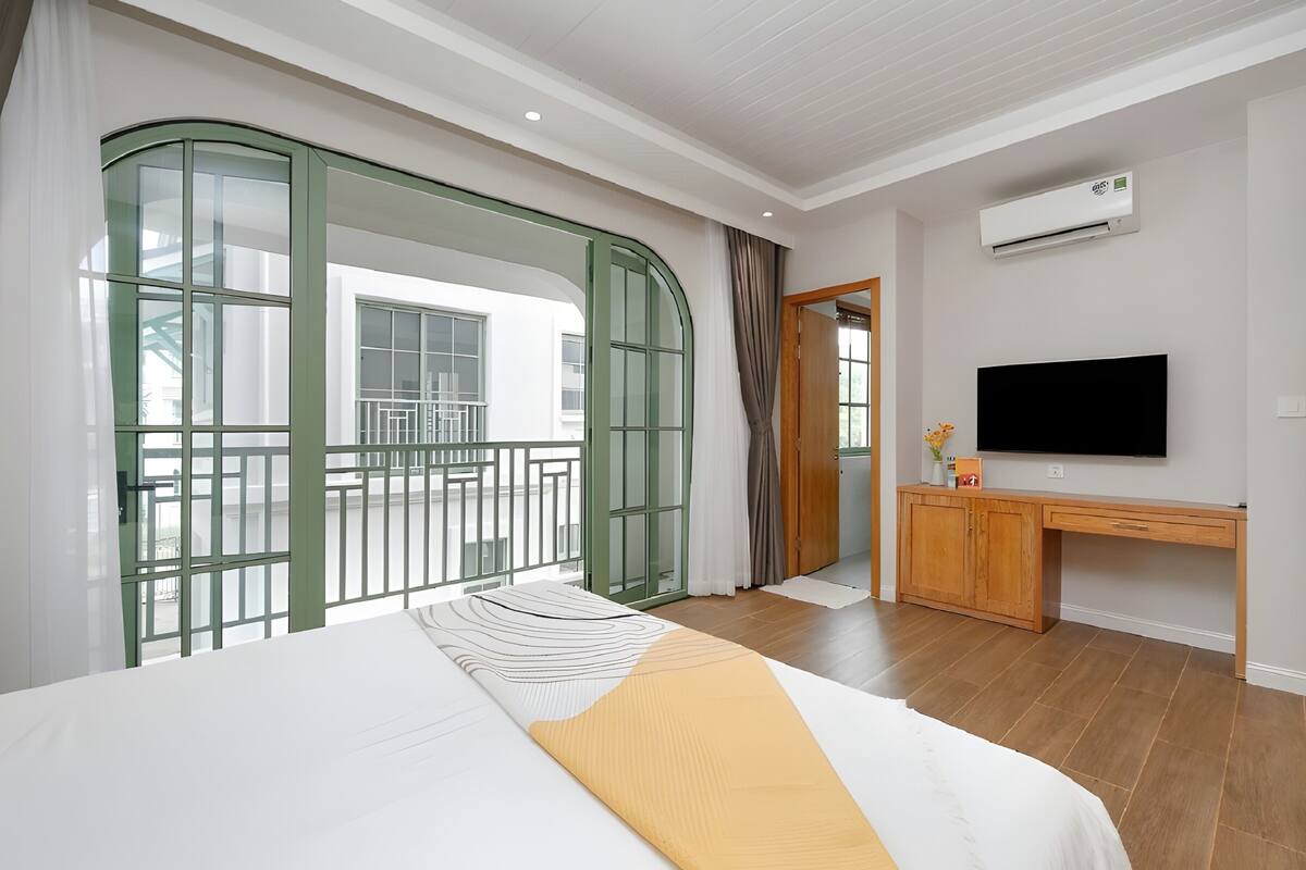 Een hotelkamer met een bed, een bureau, een televisie en een balkon met uitzicht.