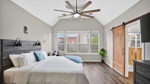 A bedroom with a bed, a ceiling fan, a large window, and a sliding door. - Spacious 4BR Retreat |Pool Table| Firepit & Hottub (Kyle)