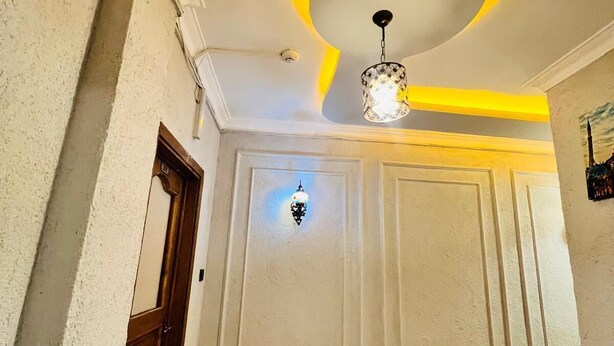 A hallway with a wooden floor, a door on the left, and a wall with a decorative ceiling. - Pembe Köşk Old City Center Sultanahmet (İstanbul)