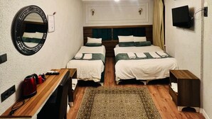 A hotel room with two beds, a desk, a mirror, a television, and a ceiling light fixture. - Pembe Köşk Old City Center Sultanahmet (İstanbul)