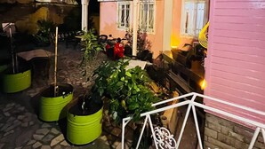 A pink building with multiple windows, a covered patio area with potted plants, and a bicycle. - Pembe Köşk Old City Center Sultanahmet (İstanbul)