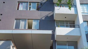 Un edificio moderno con una puerta roja, varios balcones y una escalera que lleva a la entrada.