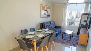Un comedor moderno con una mesa de vidrio, sillas grises y un sofá azul.