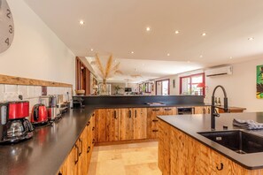 Eine moderne Küche mit Holzschränken, einer schwarzen Arbeitsplatte und einer zentralen Kochinsel mit Spüle.