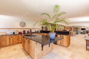 Eine Küche mit Holzschnitzereien, einer zentralen Kochinsel, einem Blumentopf und einer Backsteinwand im Hintergrund.