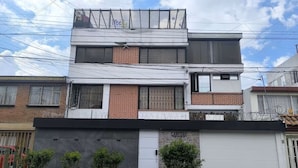 Un bâtiment à deux étages doté d’un garage, d’une porte bien visible et d’un petit jardin avec des plantes.