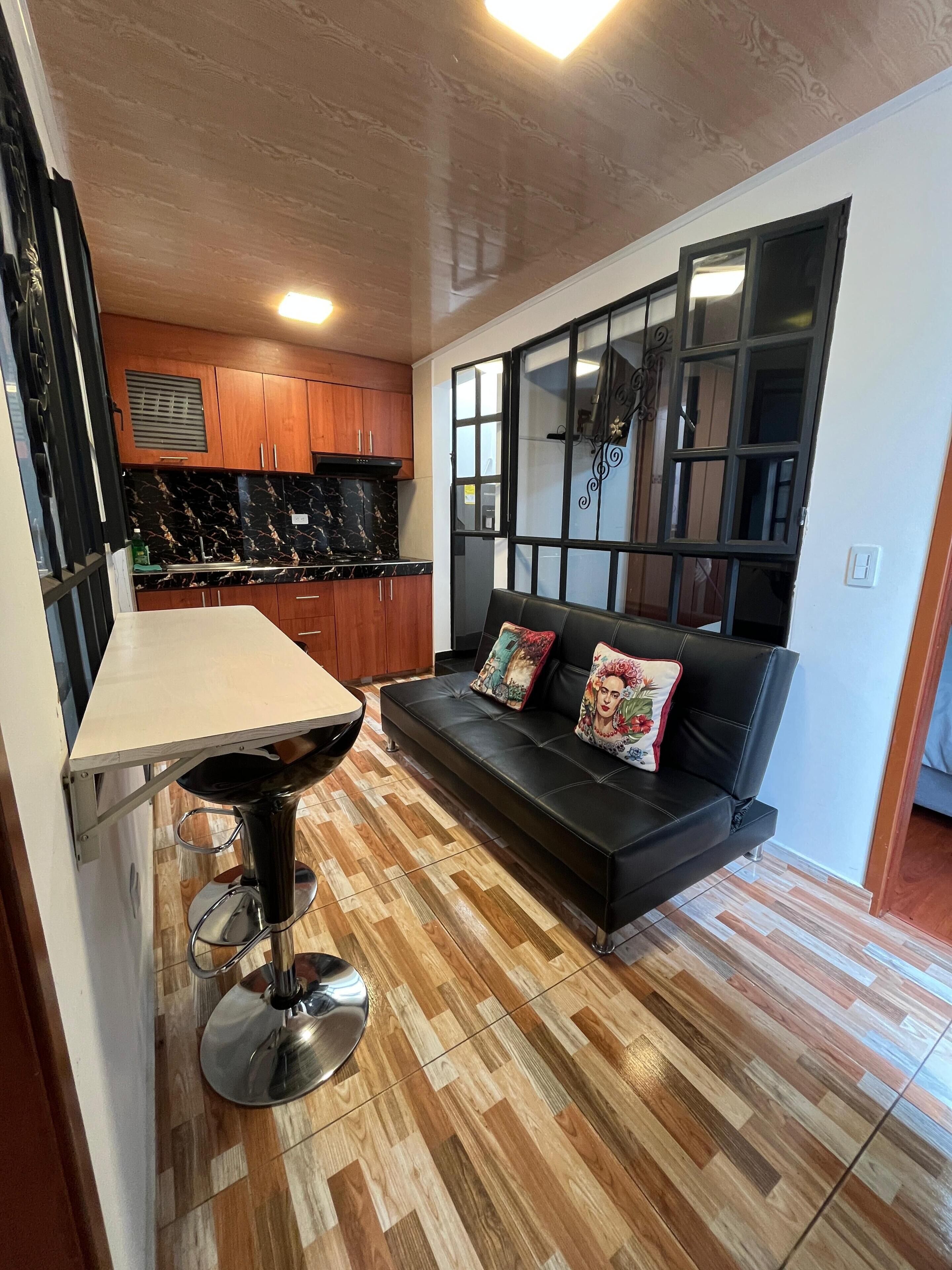 Una cocina moderna con armarios de madera, encimera de mármol y un taburete negro.