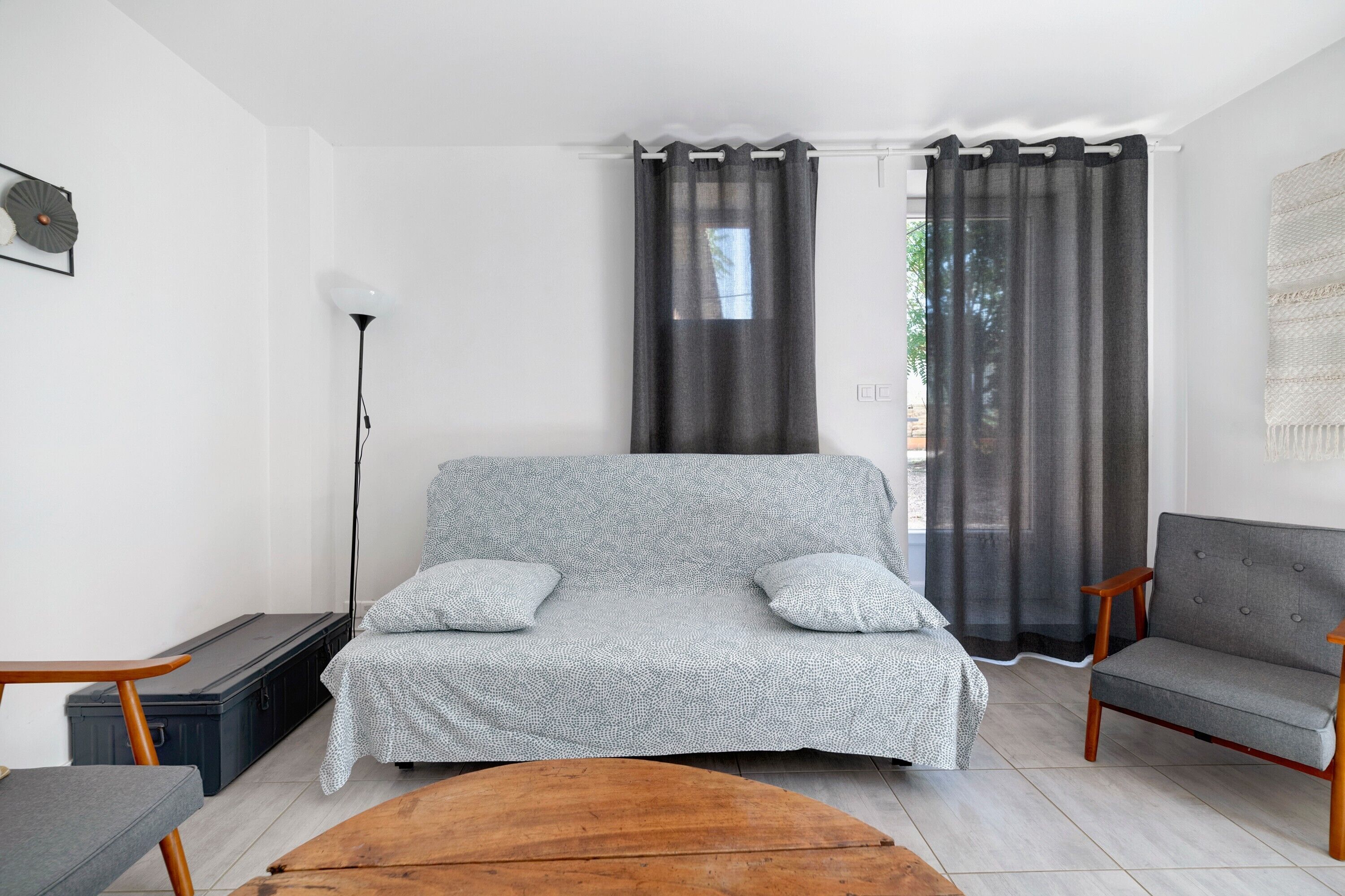 Una sala de estar con un sofá estampado, dos sillones, una mesa de centro de madera y una lámpara de pie.