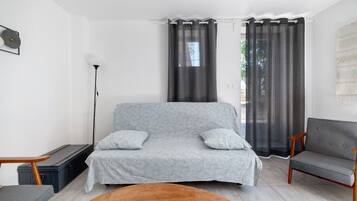 Ett vardagsrum med en mönstrad soffa, två fåtöljer, ett soffbord i trä och en golvlampa.