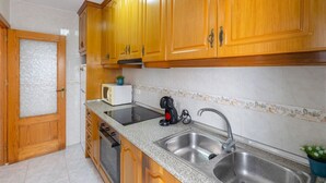 A kitchen with wooden cabinets, a stainless steel sink, a microwave, and a toaster. - Bohemian Nights by Fidalsa (Torrevieja)