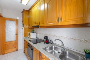 A kitchen with wooden cabinets, a stainless steel sink, a microwave, and a toaster. - Bohemian Nights by Fidalsa (Torrevieja)