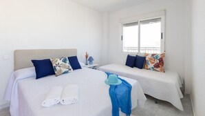 A hotel room with two beds, a window, and a nightstand with a lamp. - Bohemian Nights by Fidalsa (Torrevieja)