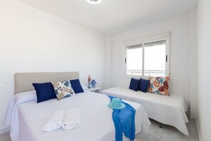 A hotel room with two beds, a window, and a nightstand with a lamp. - Bohemian Nights by Fidalsa (Torrevieja)