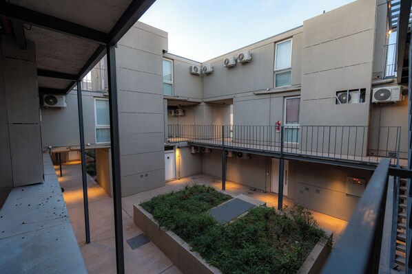 A courtyard with a garden, multiple air conditioning units, and a balcony.