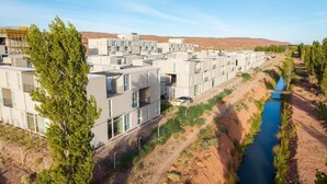 Een modern woongebied met meerlaagsgebouwen, een rivier en schaarse begroeiing.
