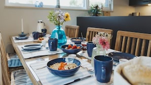 Et spisebord med blå skåle, en vase med blomster og et vindue med udsigt.