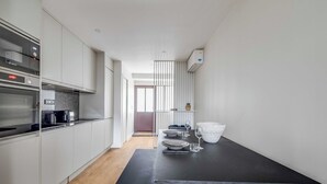 Eine moderne Küche mit weißen Schränken, einem Bosch-Backofen und einem Essbereich mit schwarzem Tisch und Stühlen.