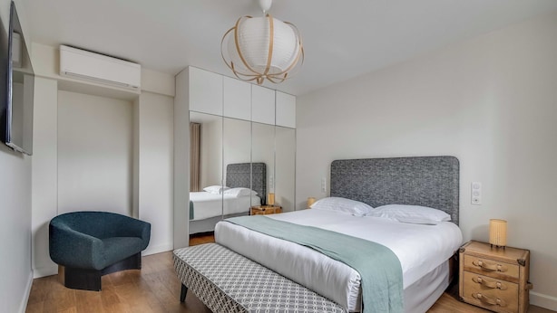 Ein Schlafzimmer mit Bett, Nachttisch, Bank und Kleiderschrank sowie einem Fernseher.