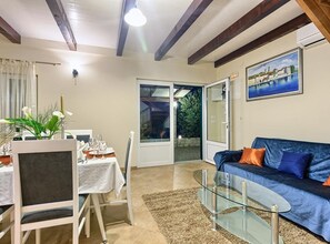 A dining area with a table set for four, a sofa, a glass coffee table, and a painting on the wall. - Villa Renata (Okrug)