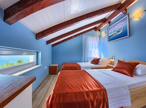 A room with two beds, a window with a view, a painting on the wall, and a wooden ceiling. - Villa Renata (Okrug)
