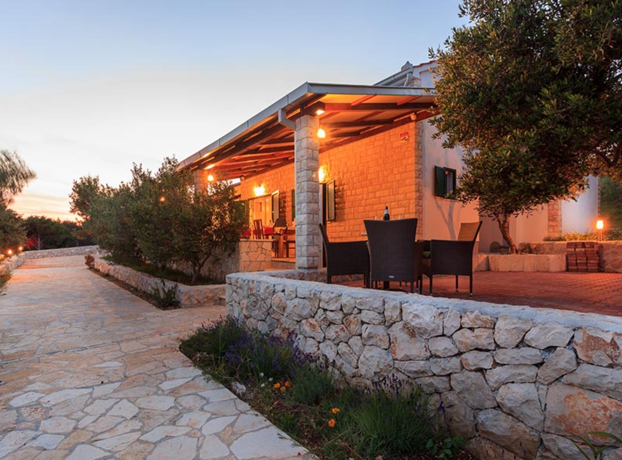 A stone-walled building with a covered outdoor seating area and a stone pathway.