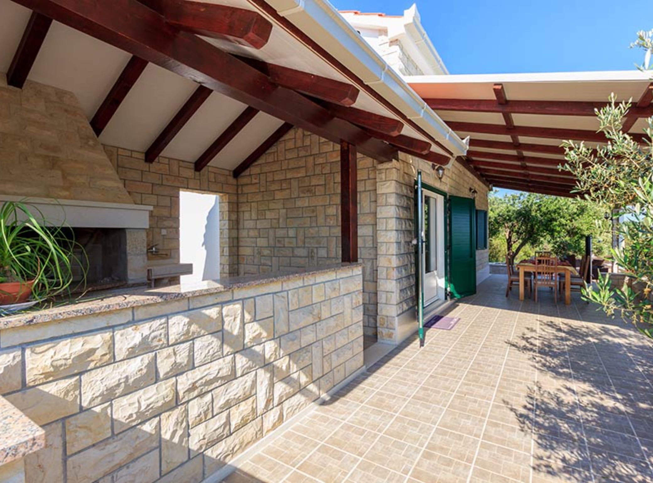 A stone building with a covered patio, a fireplace, and outdoor furniture.