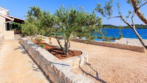 A coastal property with a stone pathway, a small tree, and a view of the sea. - Villa Renata (Okrug)