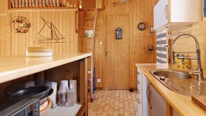 A wooden interior with a kitchen area, including a sink, cabinets, and a stove. - Holiday Home "Petite Semi-Detached Villa in the Pine Forest" with Wi-Fi (Lacanau)