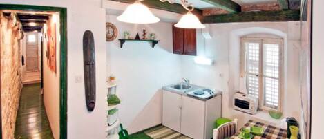 A compact kitchen with a sink, cabinets, and a window.