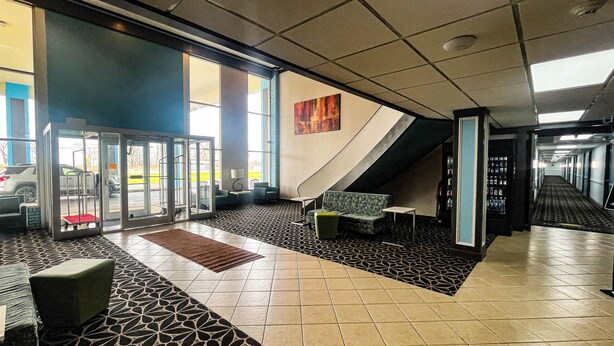 Vestíbulo de hotel con recepción, zona de estar y escalera que lleva a pisos superiores.