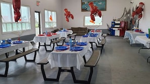 A dining hall with tables set for a meal, featuring lobster decorations and a nautical theme. - Motel & Chalets l'Acadien sur mer (Petit-Rocher)
