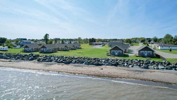 A coastal area with multiple cabins, a rocky shoreline, and a grassy field. - Motel & Chalets l'Acadien sur mer (Petit-Rocher)