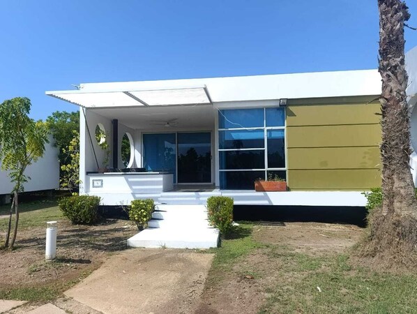 A modern building with a flat roof, large windows, and a covered porch.