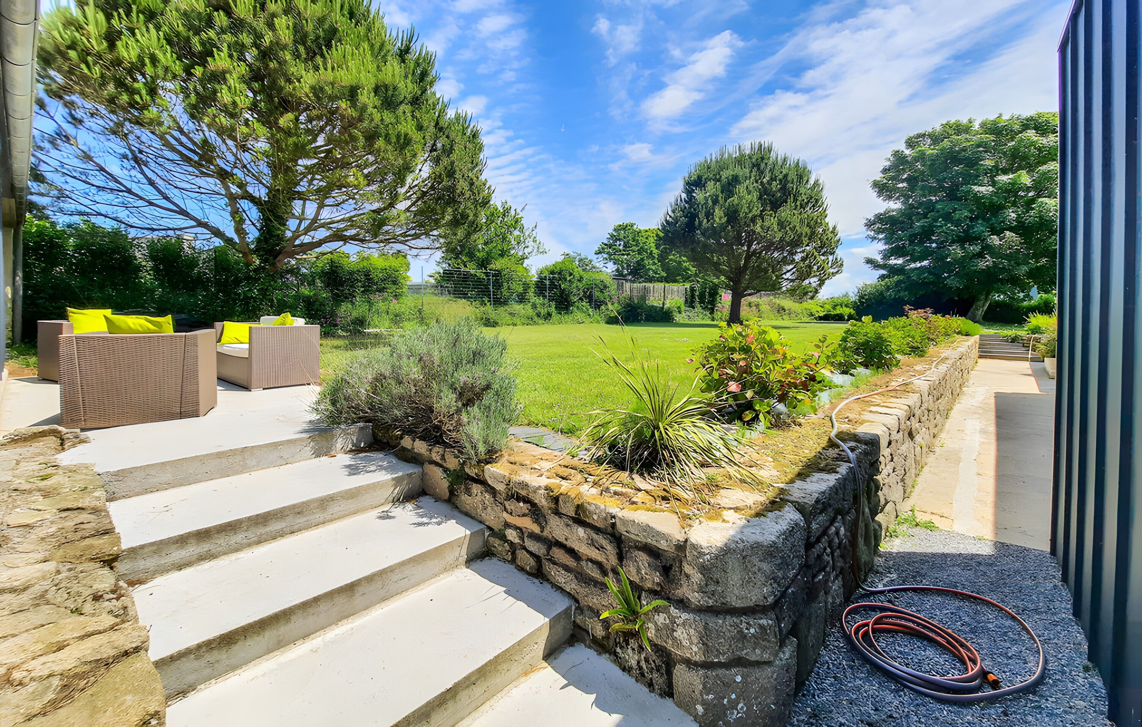 A stone staircase leading to outdoor seating with a view of a grassy yard and trees.