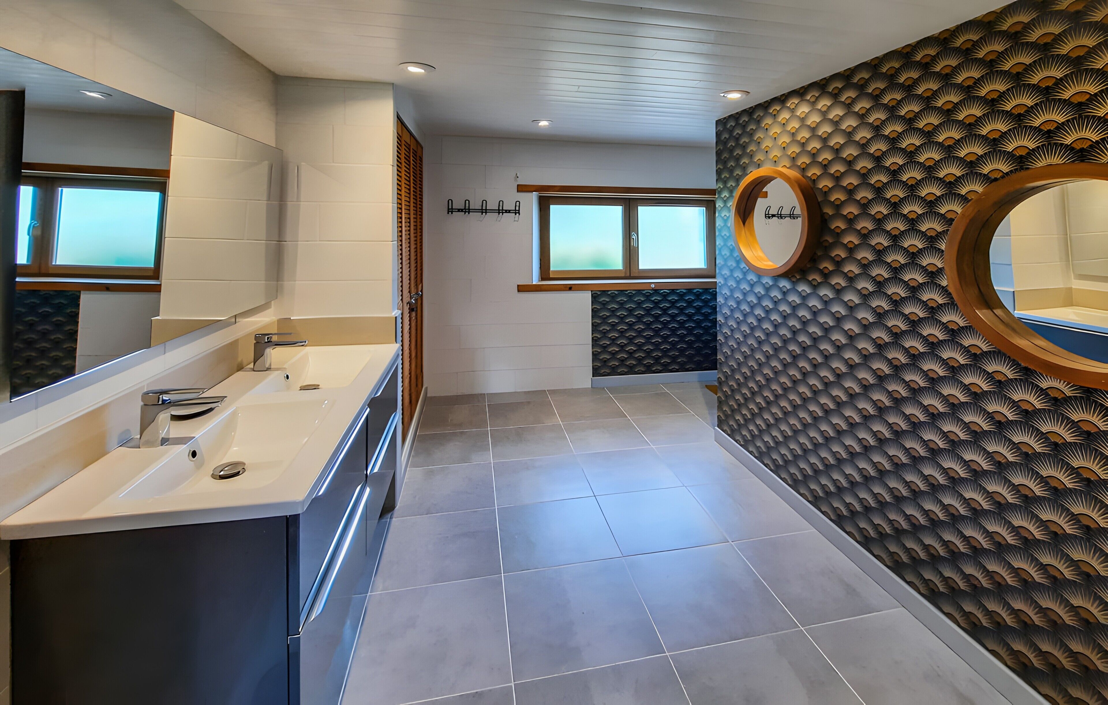 Een moderne badkamer met een wastafel, een grote spiegel en een behang met een patroon.