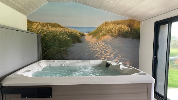 A hot tub with a view of a beach and dunes.